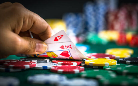 Gambling Hand Holding Poker Cards and Money Coins Chips
